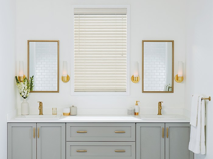 dual bathroom sink with gold accents and blinds closed over window